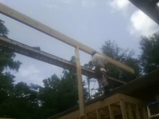 Carpenter setting a ridge beam over a new addition frame — Ice Dam Removal by Roofing Brothers in Fort Drum