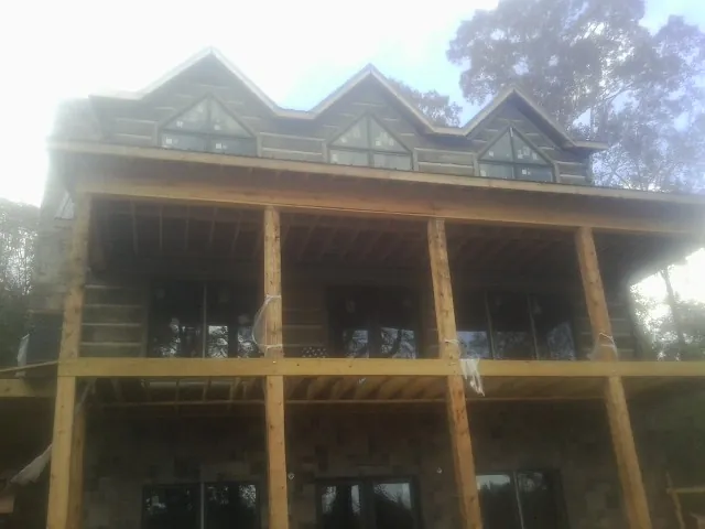 Dormers and porch framing on a large log home under construction — Roof Coating work by our crew in Fort Drum