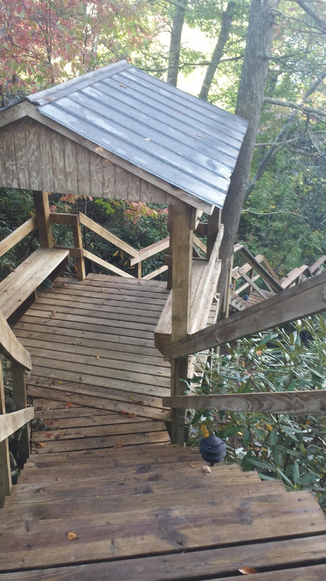Metal roofed shelter over wooden steps on a wooded walkway — Skylight Repair & Installation work by our crew in Fort Drum