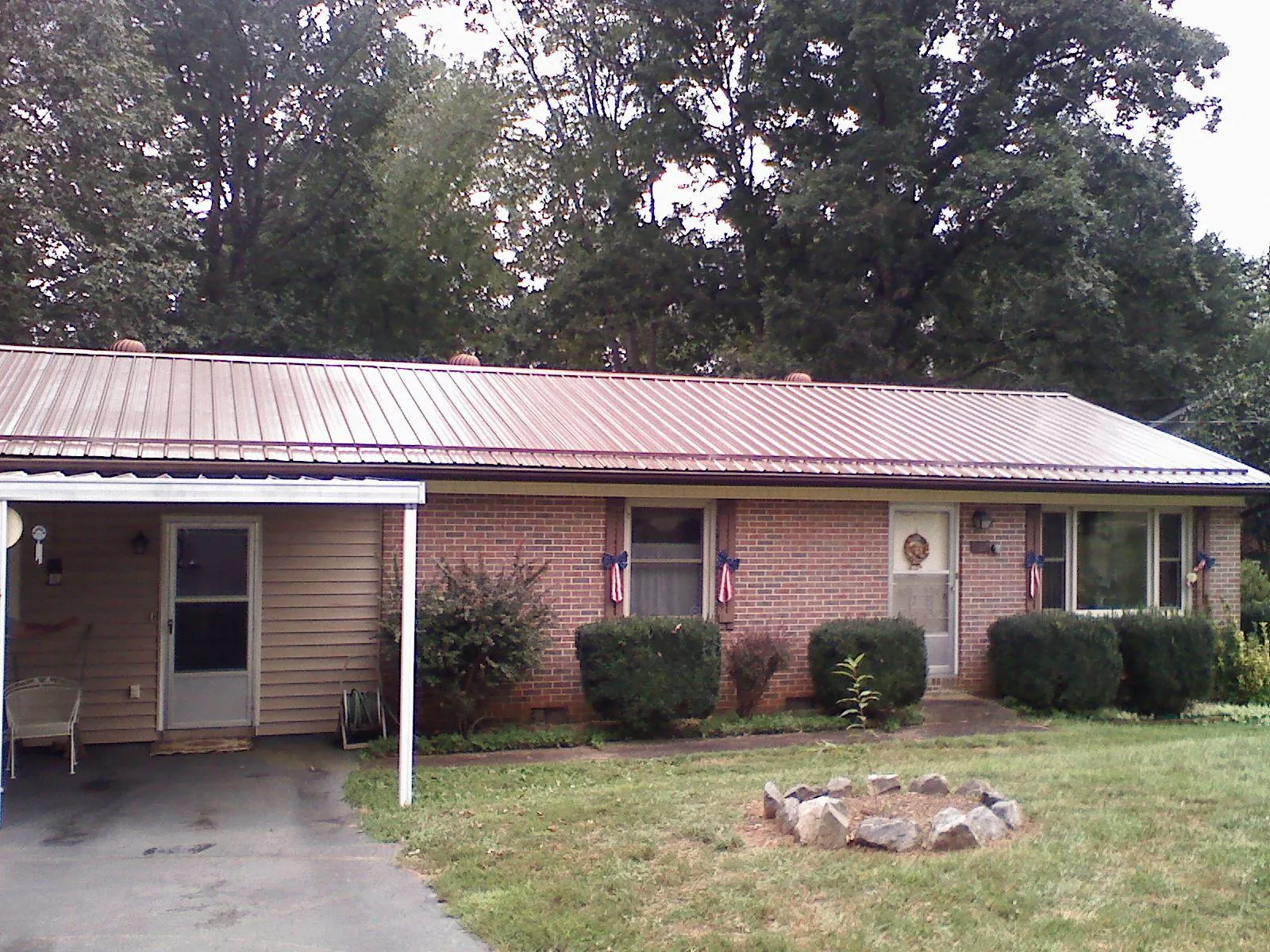 Bronze metal roof and carport on a brick ranch home — Roof Repair work by our crew in Fort Drum